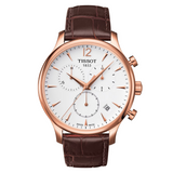 A TISSOT Tradition Chronograph watch with a white dial, rose gold case and bracelet, and a brown leather strap.