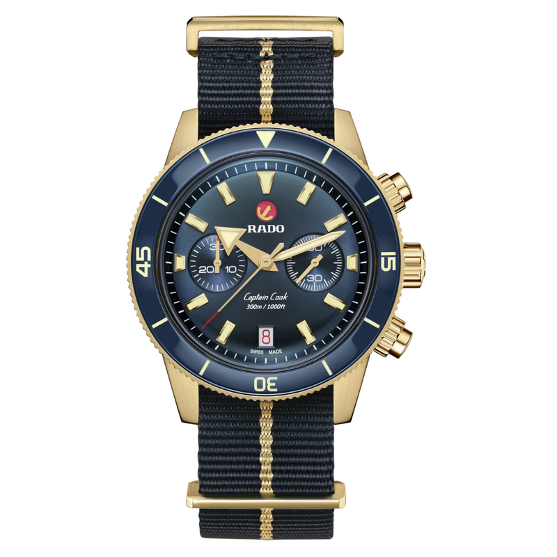 A RADO Captain Cook Automatic Chronograph watch with a blue dial, bronze case, and a black fabric strap with a gold-coloured stripe.